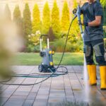 Pressure washing cleaning driveway and patio with high-pressure water spray
